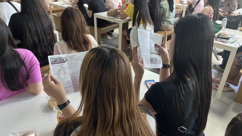 Overseas Filipinos in Taiwan browse through the UPOU brochure during the UP VINTA Learning Caravan